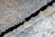 Csesznek, Hungary - Aerial top down view of winter forest crossed by asphalt road. Snowy landscape background.