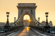 Hungary Budapest. Szechenyi Chain bridge with sunrise. Bright golden light and rising sun. Nobody in streets. Emptyness for reason of  coronavírus.