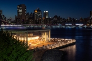 unique view about the Jane's carousel in Brooklyn bridge park in blue hour. Manhattan's Two bridges area and East river on the foreground.