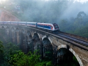 A scenic train crosses the iconic Nine Arch Bridge in Ella, Sri Lanka, surrounded by misty tropical forests, showcasing a blend of history, nature, and engineering marvel.