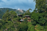 The Mahamevnawa Buddhist Monastery in Ella, Sri Lanka, sits atop a lush green hill, surrounded by mist and winding roads, offering a serene and spiritual retreat