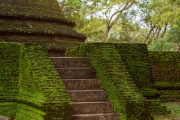 The image depicts the Vatadage, a circular relic house in Polonnaruwa’s Sacred Quadrangle, showcasing intricate stone carvings and ancient architecture under a clear sky