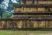 The image depicts the Vatadage, a circular relic house in Polonnaruwa’s Sacred Quadrangle, showcasing intricate stone carvings and ancient architecture under a clear sky