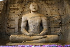 The image depicts the Vatadage, a circular relic house in Polonnaruwa’s Sacred Quadrangle, showcasing intricate stone carvings and ancient architecture under a clear sky