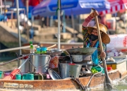 chef woman in her boat in thailand a floating market. She sell all day her traditional food. This floating market is a popular tourist attraction near by Bangkok.