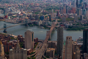 Aerial cityscape about New York city. The east river in the middle. Manhatttan and Brooklyn bridges are over the river. Brooklyn is on the background.